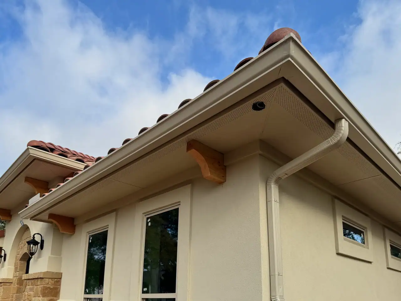 Stucco casita with a stone base, tile roof, and arched entry in Driftwood