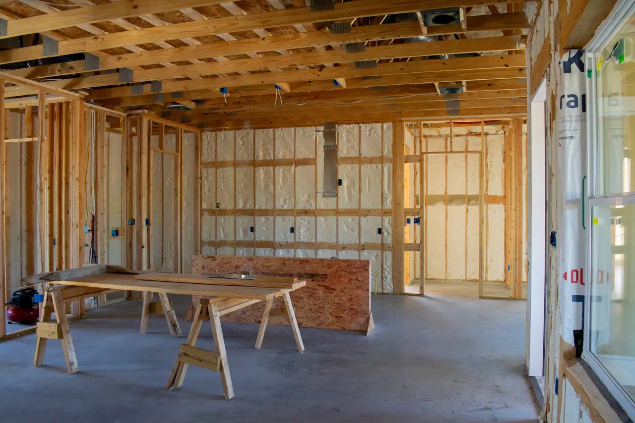 Insulated walls and open ceiling framing inside the home before drywall