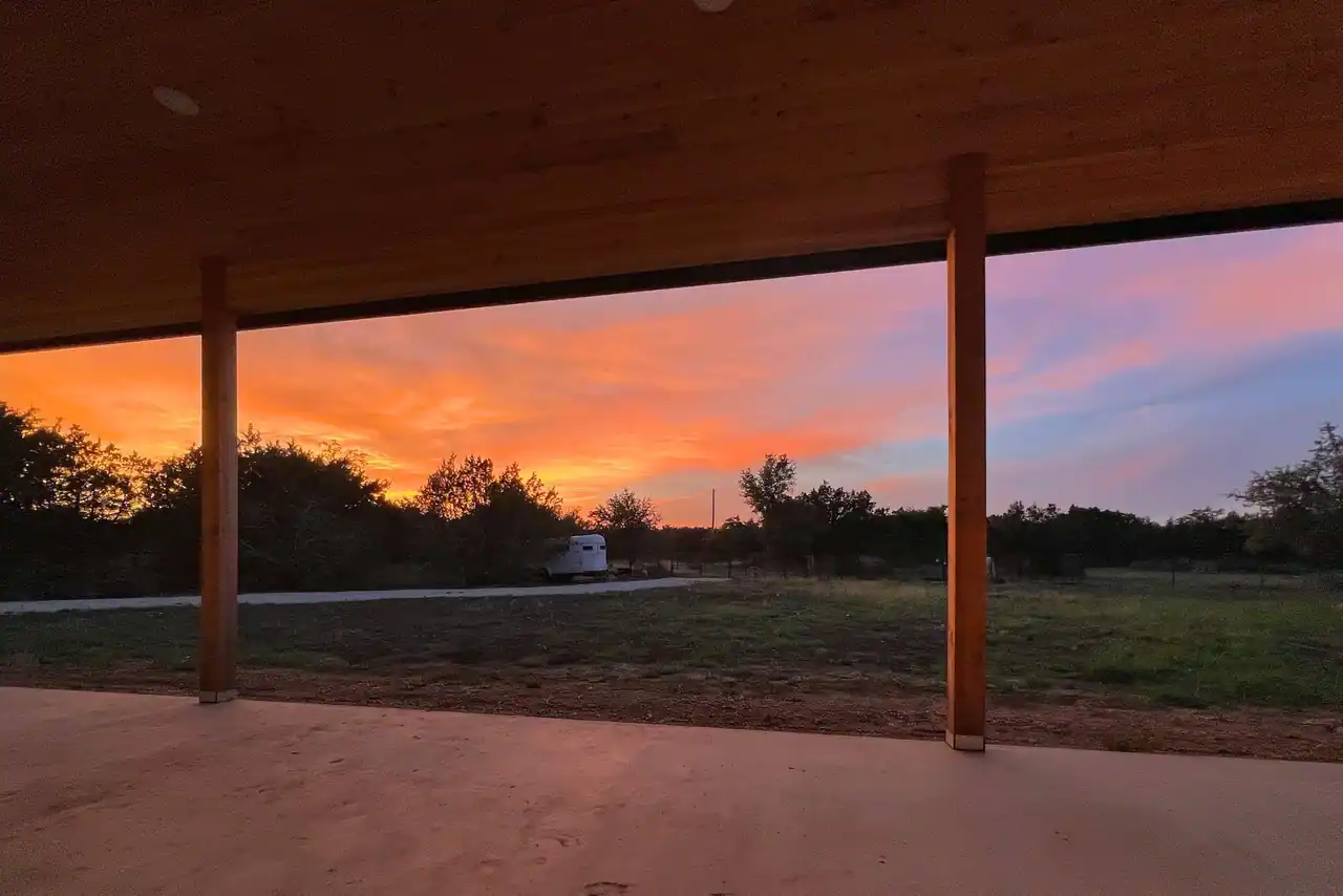 Covered porch of a barndominium at sunset, looking over open land near San Marcos