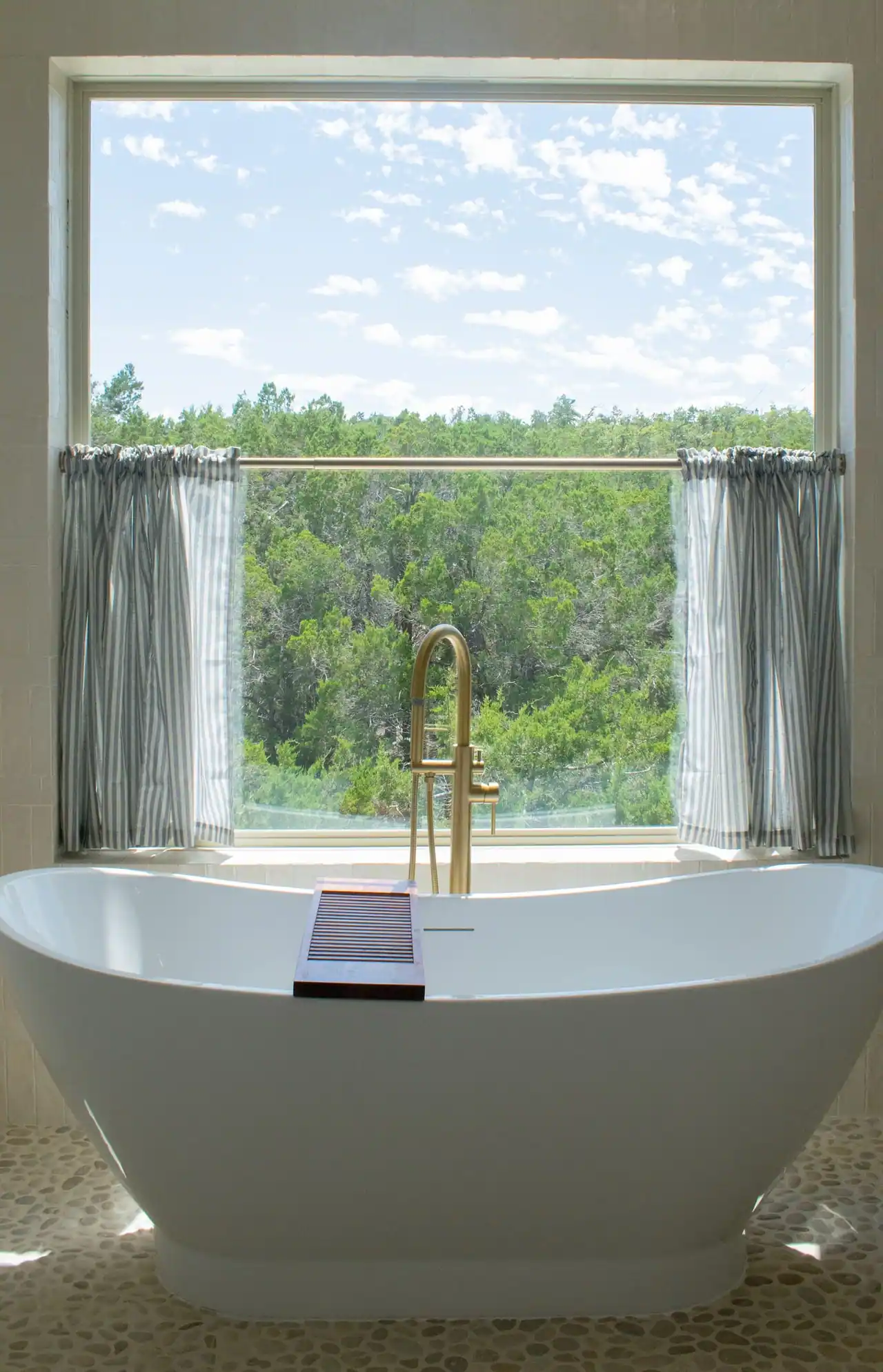 Soaking tub with brass filler overlooking Hill Country trees