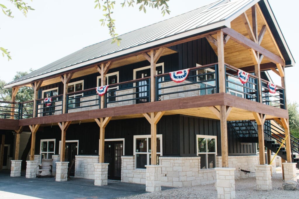 Two-story black barn with wraparound balcony and bunting