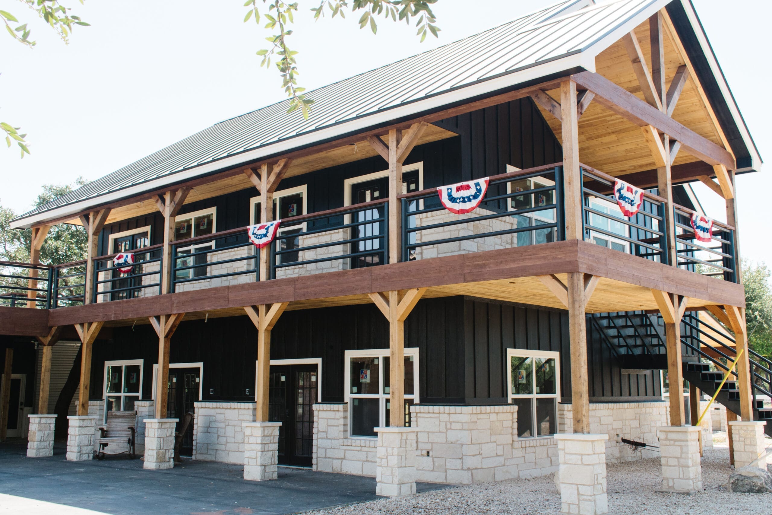 Two-story black barn with wraparound balcony and bunting