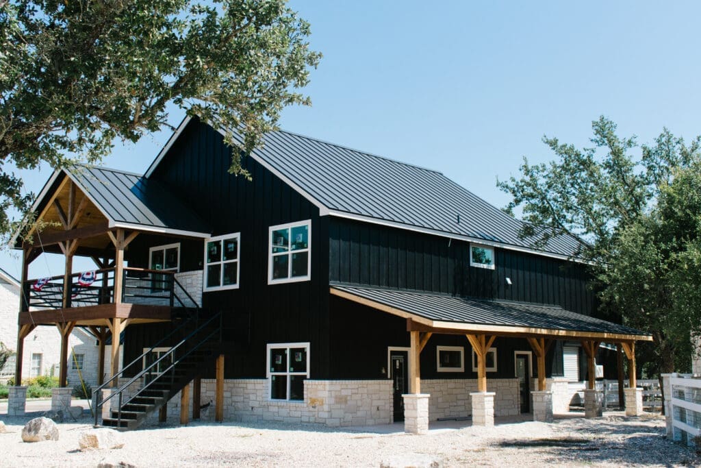 Two-story black party barn with covered porches in the Hill Country
