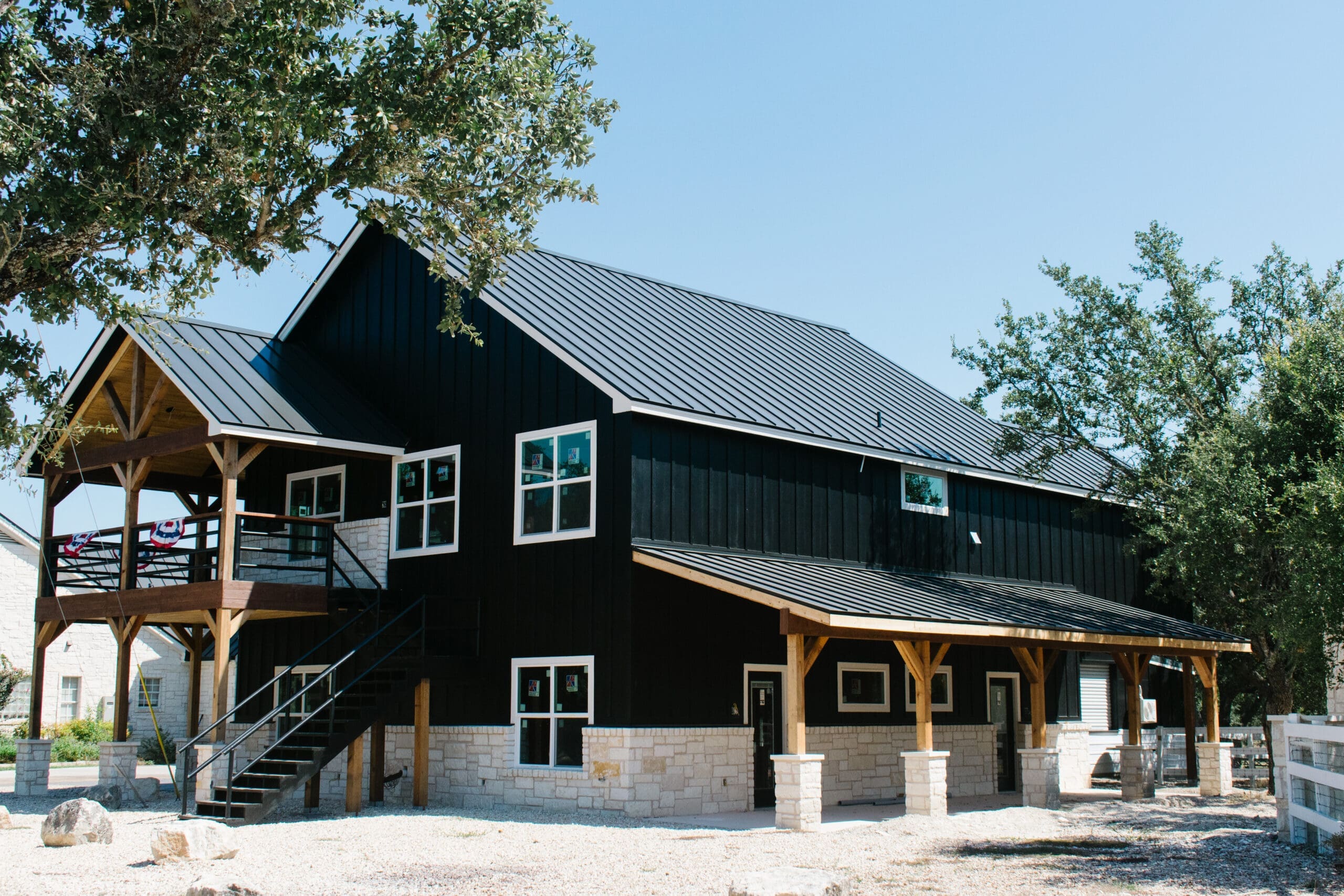 Two-story black party barn with covered porches in the Hill Country