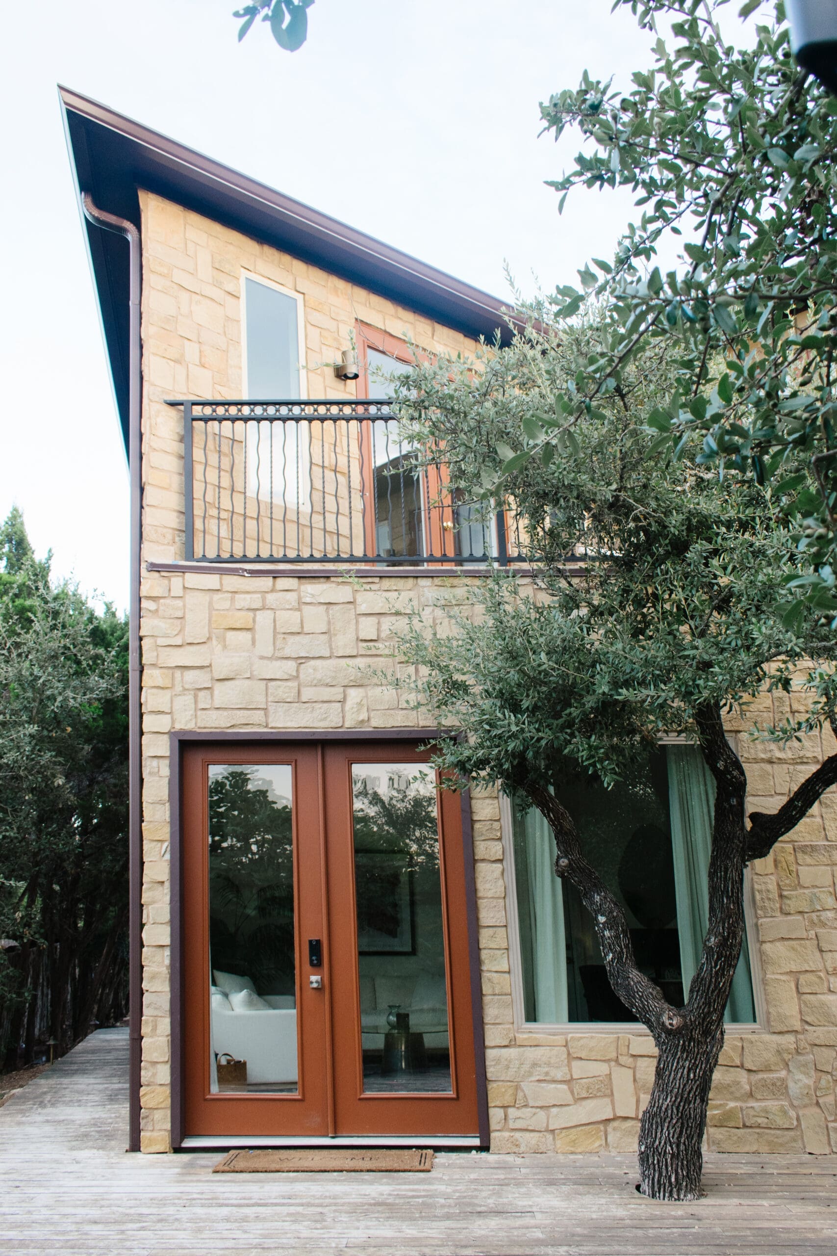 Stone home exterior with balcony and mature oak trees