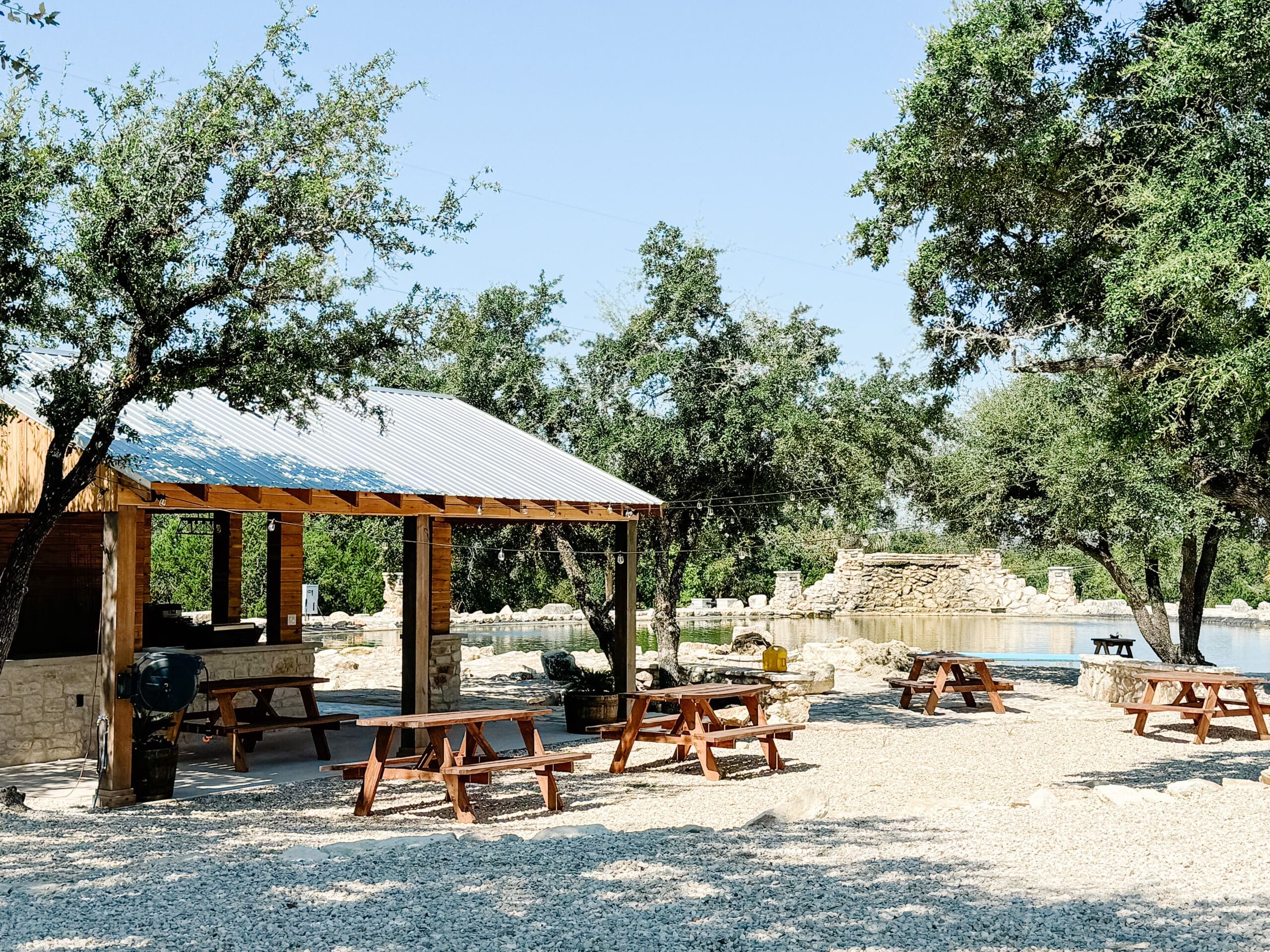 Timber pavilion, stone pool, and mature oaks on a Ridge Rock Hill Country property