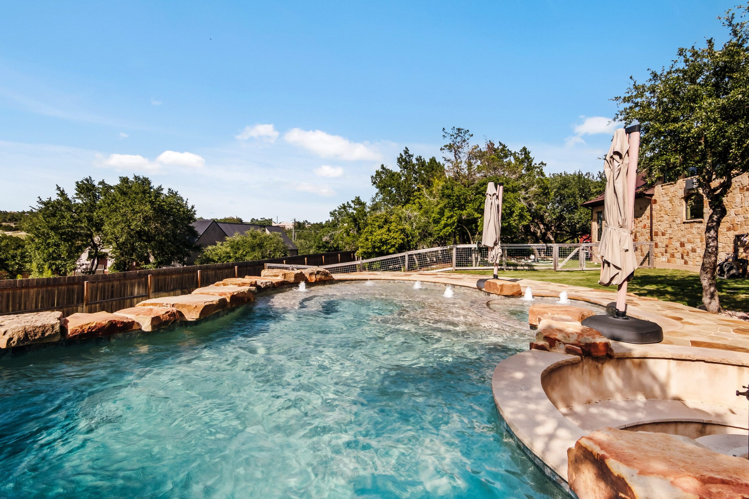 Custom pool with fountain jets and stone spa beside a Hill Country home built by Ridge Rock Builders