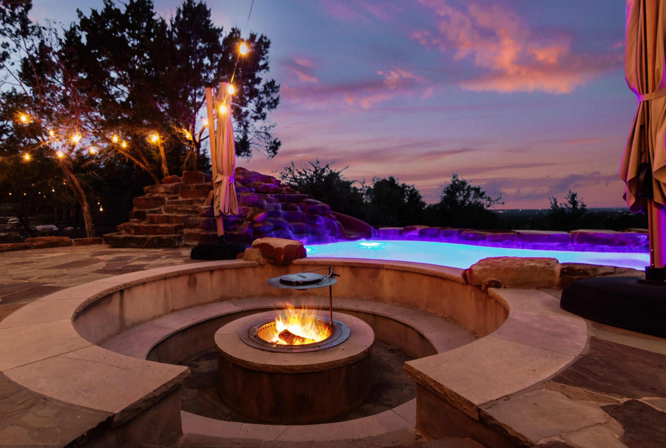 Custom stone pool and spa at twilight with Hill Country views at a Ridge Rock Builders home in Dripping Springs