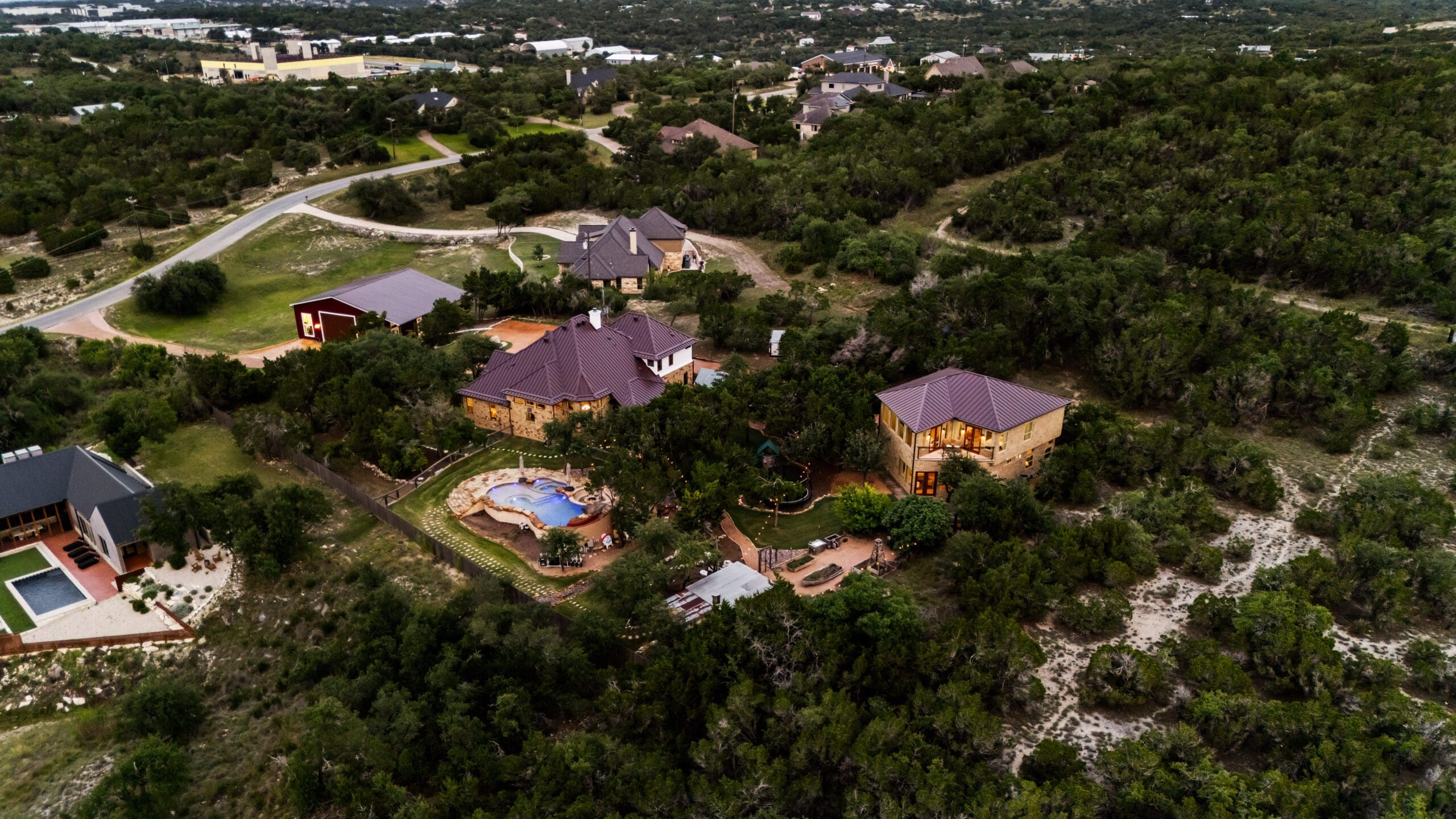 Evening aerial of a custom home and guest casita on Dripping Springs acreage