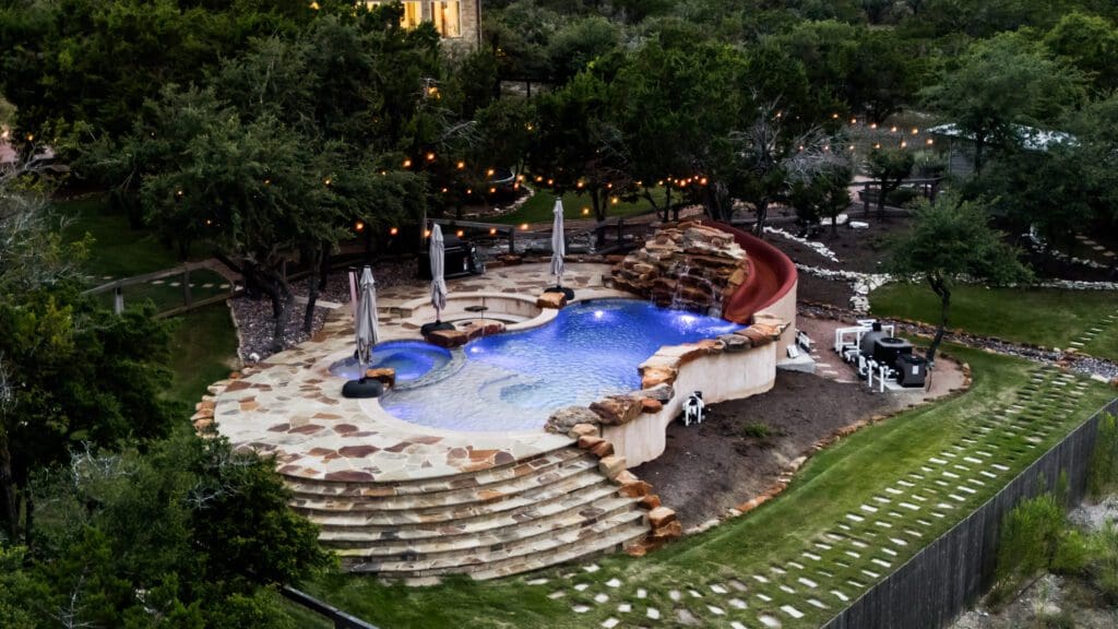 Aerial view of a custom rock pool with waterslide at a Hill Country home