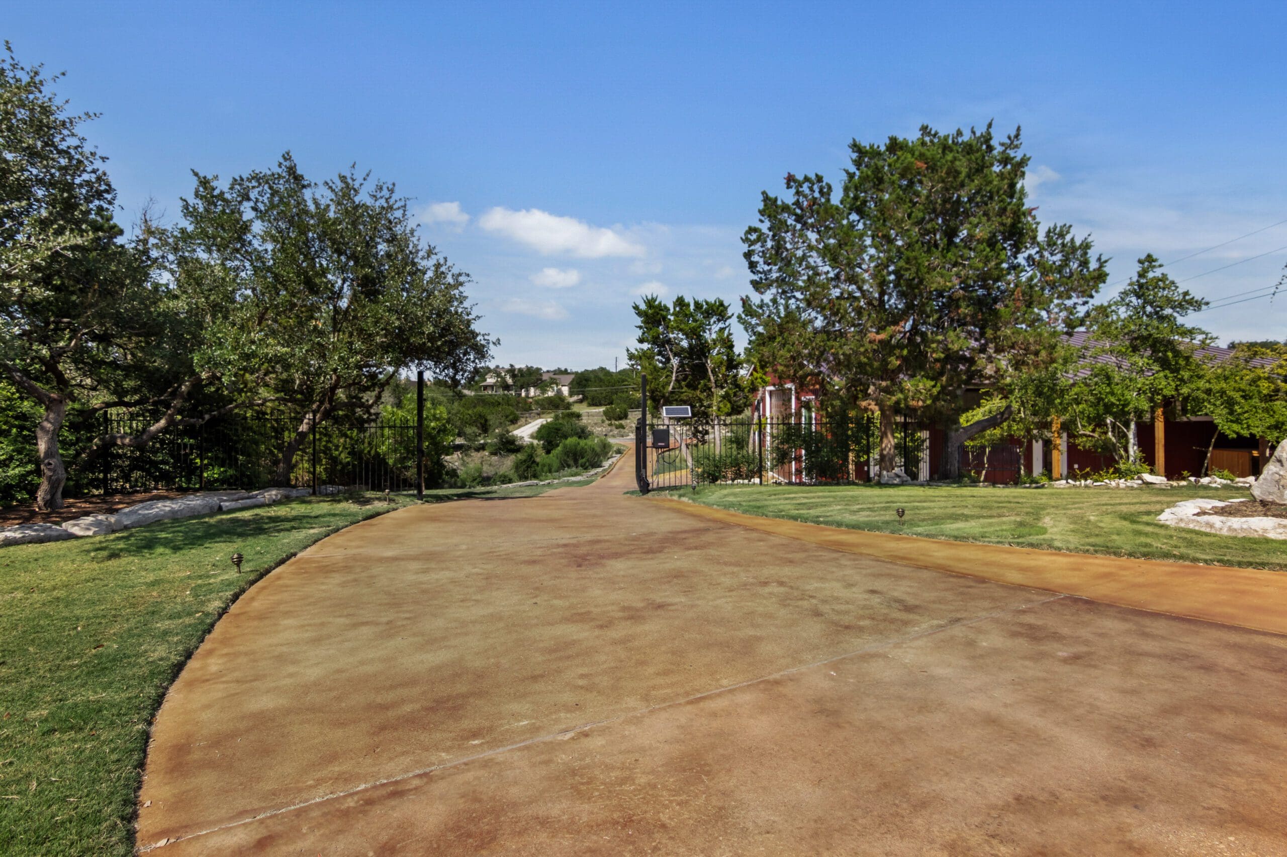 Stained concrete drive winding through oak trees on a Hill Country property