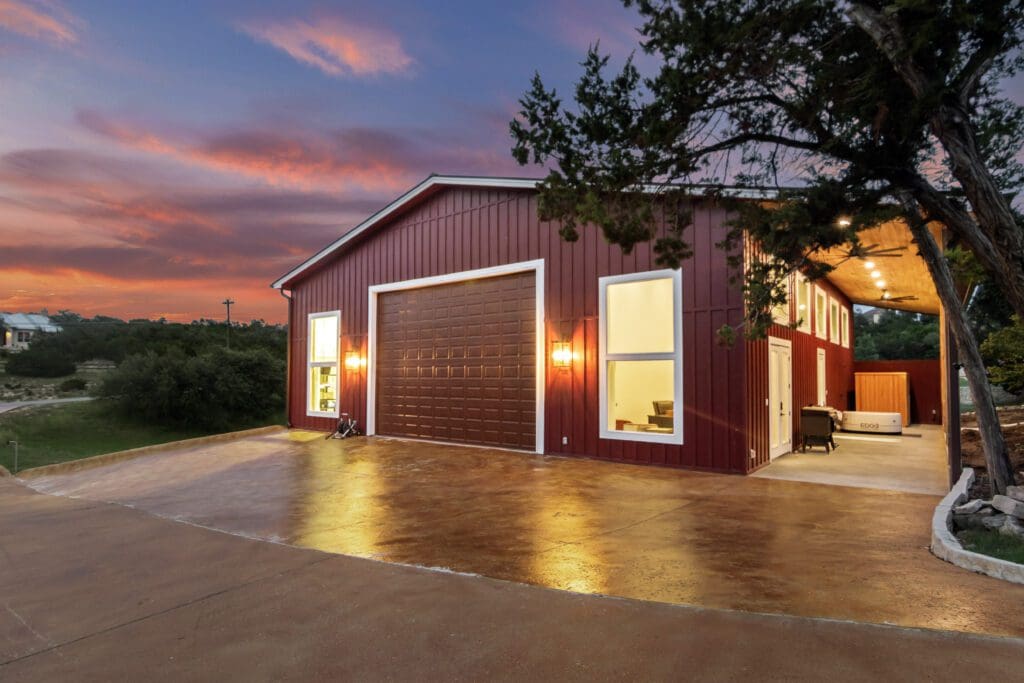 Finished Boat Barn shop lit at dusk on a Hill Country property